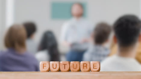 Education-Concept-With-Wooden-Letter-Cubes-Or-Dice-Spelling-Future-With-Student-Lecture-In-Background